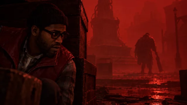 Simon Ordell crouches behind crates in Silent Hill Townfall's red, ash-filled square as a monster passes a twisted monument.